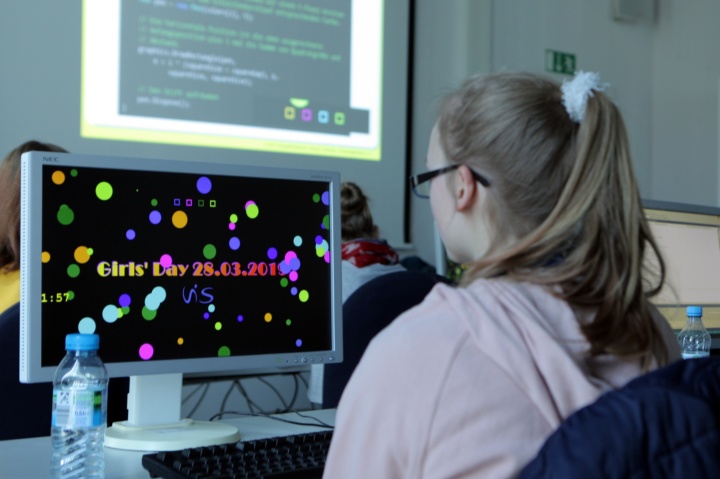Ein Mädchen sitzt vor einem Computerbildschirm und kreiert ihren eigenen Bildschirmschoner.