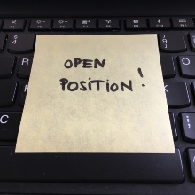 Yellow post-it note stuck to a keyboard with the words "Open Position" written on it in black capital letters